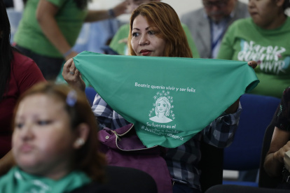 Una mujer muestra hoy una pañoleta verde con la imagen de Beatriz, mientras observa la transmisión en vivo de una audiencia de la CorteIDH, en San Salvador (El Salvador). EFE/Rodrigo Sura