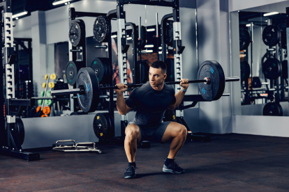 A strong man doing deadlift with weights in a gym.
