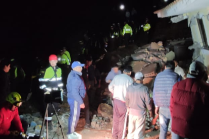 Bomberos de Alausí intentan rescatar a personas atrapadas bajo una de las casas.