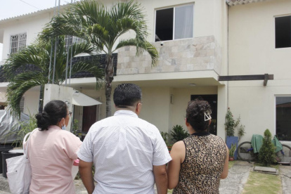 Vecinos observan, consternados, la casa donde el lunes 20 de marzo tres miembros de una familia murieron intoxicados.