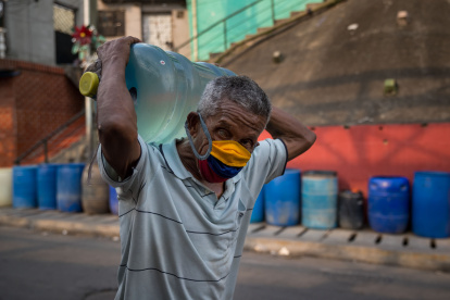Caracas. Un hombre al cargar un botellón de agua potable suministrado por un camión cisterna en un barrio popular de esta capital sudamericana.