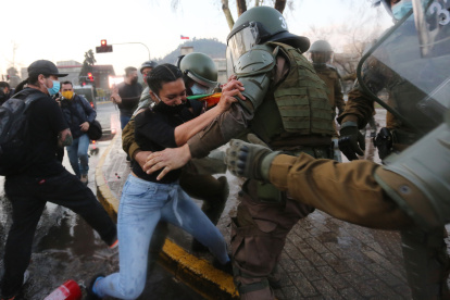 Fotografía de archivo, tomada en septiembre de 2020, en la que se registró a un grupo de carabineros chilenos al forcejear con una manifestante, en Santiago de Chile.