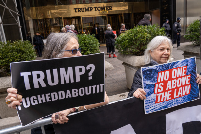 Unas personas sostienen pancartas en contra del expresidente Donald Trump durante una manifestación frente a la Torre Trump, ubicada en la Quinta Avenida, en Nueva York (Estados Unidos). En las inmediaciones de la corte donde se juzgará al expresidente, en el Bajo Manhattan, una veintena de medios están apostados esta mañana a la espera de que aparezcan manifestantes favorables al presidente, pero ni ayer por la noche ni hoy por la mañana apareció uno solo de ellos. En la Torre Trump, en la Quinta Avenida neoyorquina, se vive el mismo panorama: ni anoche ni hoy se han presentado manifestantes de uno u otro signo, y solo es posible ver a los equipos de televisión apostados frente al vallado extendido por la policía a ambos lados de la avenida. EFE/ Ángel Colmenares