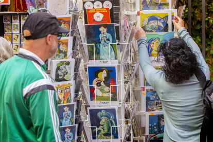MÁLAGA, 08/04/2023.- Unos turistas miran postales con obras del pintor Pablo Ruiz Picasso en el entorno del museo que lleva su nombre en el centro de la ciudad de Málaga en el día del 50 aniversario del fallecimiento del artista, este sábado. EFE/ Álvaro Cabrera