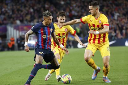 BARCELONA, 10/04/2023.- El atacante brasileño del FC Barcelona Raphinha (i) disputa una posesión con el centrocampista Toni Villa (c) y su compañero Javi Hernández, del Girona FC durante el partido de fútbol de la jornada 28 de LaLiga que FC Barcelona y Girona FC juegan este lunes en el Camp Nou. EFE/Toni Albir