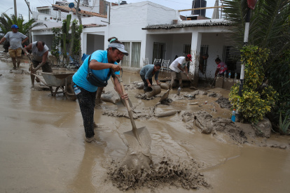 Personas ayudan a remover el lodo en una calle afectada por las lluvias, en el balneario de Punta Hermosa al sur de Lima (Perú), en una fotografía de archivo.