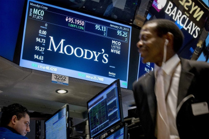 Bolsa.- Una pantalla muestra la información del ticker de Moody"s mientras los operadores trabajan en el piso de la Bolsa.