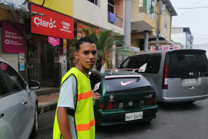 Jornada labora. Kevin recorre una de las calles del centro de Quevedo, donde cuida carros. Es su punto de trabajo.