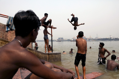 Niños indios saltan al río Ganges mientras se refrescan durante una calurosa tarde en Calcuta, India, el 18 de abril de 2023.
