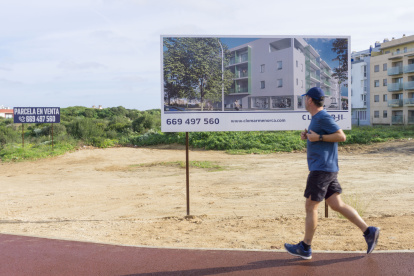 Un hombre pasa frente a una publicidad de venta de obra nueva en Maó, Menorca, este lunes.