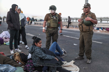 Policías hablan con migrantes en el paso fronterizo de control entre Santa Rosa (Perú) y Chacalluta (Chile), el jueves 27 de abril de 2023. El presidente del Congreso de Chile, Vlado Mirosevic, lanzó este viernes la idea de crear "un corredor" humanitario para solucionar la crisis migratoria en la frontera norte, donde cientos de personas se agolpan desde hace dos días tratando de salir de Chile e ingresar en Perú de forma irregular. EFE/ Aldair Mejía