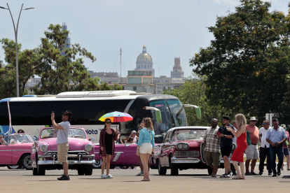 AME5338. LA HABANA (CUBA), 30/04/2023.- Turistas se toman fotografías con autos clásicos, el 28 de abril de 2023 en La Habana (Cuba). La Feria Internacional de Turismo de Cuba comienza este lunes en La Habana en medio de una profunda crisis que complica la recuperación de un sector a su vez vital -por tamaño y acceso a divisas-, para reanimar la maltrecha economía nacional. EFE/ Ernesto Mastrascusa