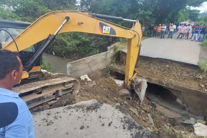 Una retroexcavadora prepara el terreno para levantar un paso vehicular temporal.