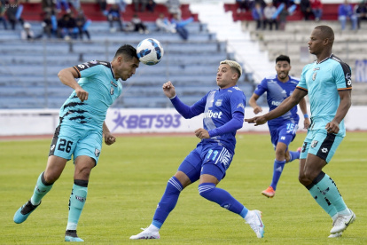 El central Arián Pucheta (i), de Cumbayá, despeja un balón ante la marca del extremo Diego García (c), de Emelec.