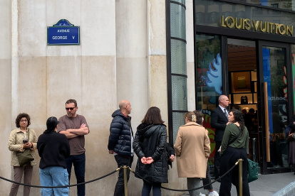Varias personas esperan en la puerta de una tienda de lujo este sábado en París.
