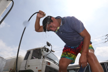 El calor hace que las personas se refresquen con agua en las gasolineras de la avenida de Las Américas,