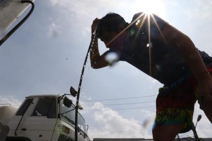 Necesidad. Los habitantes hacen paradas en las gasolineras de Guayaquil para mojarse el rostro y la cabeza, y lograr así aplacar en algo el calor y la humedad.