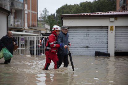 Un miembro de la Cruz Roja Italiana ayuda a las personas a salir de sus apartamentos tras la crecida del río Savio, en Cesena, Italia, el 16 de mayo de 2023.