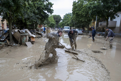 Personas trabajan para limpiar una calle anegada tras las inundaciones que están afectando a la región de Emilia-Romaña, en Faenza, Italia, el 19 de mayo de 2023.