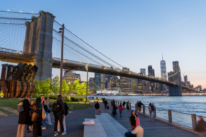 Varias personas transitan por el parque de Dumbo, ubicado a un costado del puente de Brooklyn.