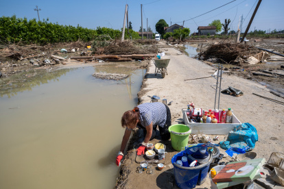 Una mujer lava vajilla en una zona inundada entre escombros, en Ca" di Lugo, un pequeño pueblo de Lugo (Ravenna), tras la crecida del río Santerno, en el norte de Italia, el 23 de mayo de 2023.