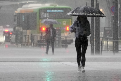 Una mujer joven camina bajo fuertes lluvias en Tokio, Japón, el 2 de junio de 2023. El aire cálido y húmedo generado por el tifón Mawar fluyó hacia el frente de la temporada de lluvias