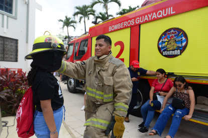 Un bombero le coloca su casco a una niña.