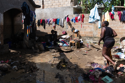 Una mujer camina entre ropa y enseres dañados por el lodo producto de las intensas lluvias en Haití.
