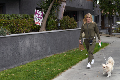 Evidencia. Una mujer pasea con su perro junto a un anuncio de alquiler de departamentos en Los Ángeles.