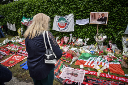 Una mujer mira flores, pancartas y bufandas cerca de la entrada a Villa San Martino en Arcore, donde el ataúd de Silvio Berlusconi fue llevado un día antes, cerca de Milán, en el norte de Italia, el 13 de junio de 2023.