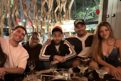 Shakira junto a Lewis Hamilton y un grupo de amigos celebrando en un restaurante.
