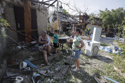 Una mujer y un niño entre los daños en el sitio alcanzado por la caída de escombros de un cohete, en la aldea de Stari Petrivtsi cerca de Kyiv (Kiev), Ucrania, el 16 de junio de 2023