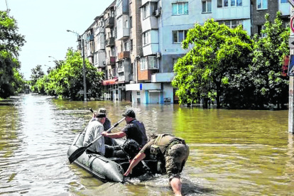 Personas se mueven en un bote inflable por las calles de la inundada ciudad de Jersón.