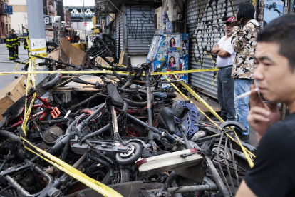 Personas observan un montón de bicicletas eléctricas quemadas cerca del lugar donde se produjo un incendio nocturno en Nueva York, este 20 de junio de 2023.