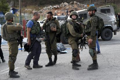 Oficiales de las fuerzas de seguridad israelíes hacen guardia junto al cuerpo de un presunto atacante en la escena de un tiroteo en el asentamiento de Eli, entre Nablus y Ramallah, en Cisjordania, el 20 de junio de 2023