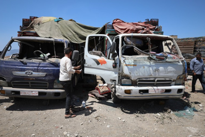 Las personas se paran junto a los camiones dañados en un mercado de verduras tras uno de los ataques.