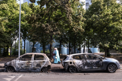 La gente pasa por delante de un coche incendiado en la avenida Pablo Picasso tras una noche de disturbios civiles, en Nanterre, cerca de París, Francia, el 28 de junio de 2023.
