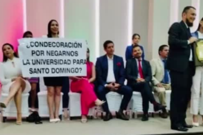 Liliana Silva sostiene un cartel de rechazo, mientras Viviana Veloz (der.) es reconocida en Santo Domingo