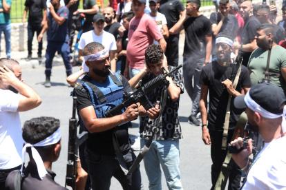Un militante palestino dispara al aire mientras asistía al funeral de los dos hombres muertos durante una redada israelí en la ciudad de Nablus.