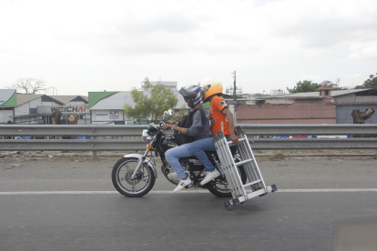 Ocupantes de moto movilizan una escalera metálica.