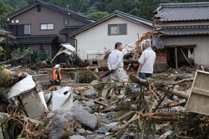 Personas observan los daños sufridos en las casas por las inundaciones y deslizamientos causados por las lluvias en Kurume, Japón.