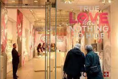 Tienda.- Una pareja observa relojes en un almacén, que en la vitrina dice que el verdadero amor no tiene nada que esconder.