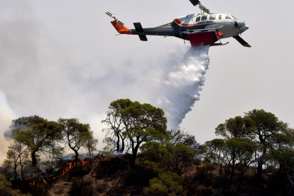 Un avión de extinción de incendios arroja agua para extinguir un incendio forestal que está quemando una zona forestal frente a las instalaciones de la refinería de Motor Oil, cerca de Loutraki, Grecia.