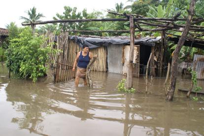En la imagen un registro de archivo de una mujer frente a su casa inundada en el municipio de Monjaras (sur de Honduras).