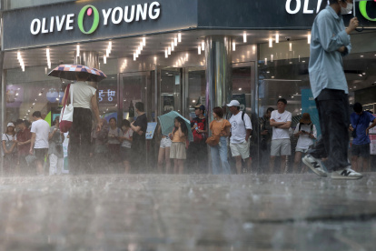 Turistas extranjeros se ven atrapados en una lluvia repentina en la calle Myeongdong en Seúl, Corea del Sur, el 31 de julio de 2023, en medio de una alerta de ola de calor.EFE/EPA/YONHAP SOUTH KOREA OUT