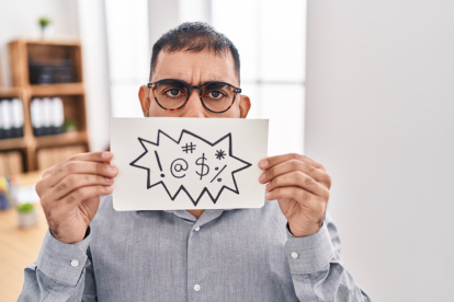 Middle east man with beard holding banner with swear words angry and mad screaming frustrated and furious, shouting with anger. rage and aggressive concept.