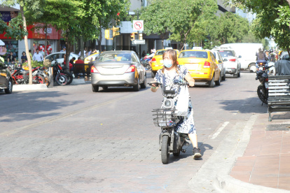 Una mujer maneja una moto en contravía en plena avenida 9 de Octubre, de Guayaquil.