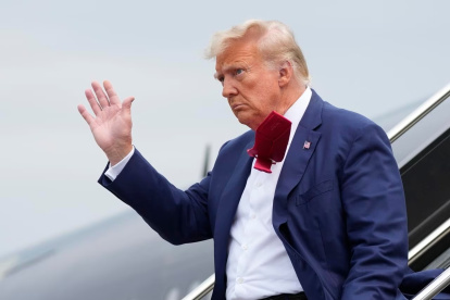 Donald Trump saluda a los presentes mientras se baja de su avión, en su camino a enfrentar un juez por acusaciones federales de conspirar para revertir las elecciones 2020.