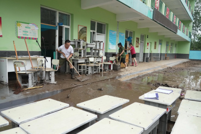 Profesores limpian el agua acumulada en el pueblo de Qizhongkou en la provincia de Hebei.