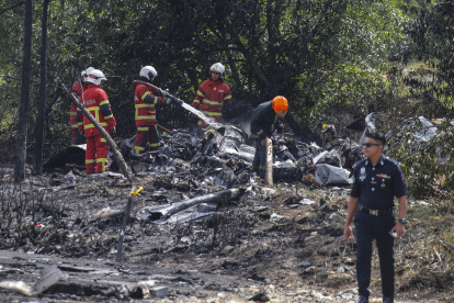 Oficiales del Depmento de Bomberos y Rescate de Malasia inspeccionan la escena del accidente de una avioneta en Elmina, estado de Selangor, Malasia. EFE/EPA/FAZRY ISMAILarta